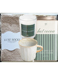 Packaged gift set with mug, candle, and cocoa mix on a white background
