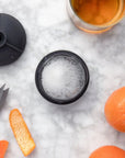 Charcoal Single Sphere Ice Mold with ice cube, surrounded by whiskey and orange slices