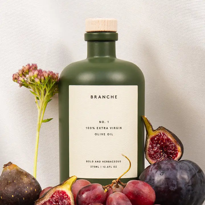 Green bottle of Branche olive oil with fruits on a neutral background