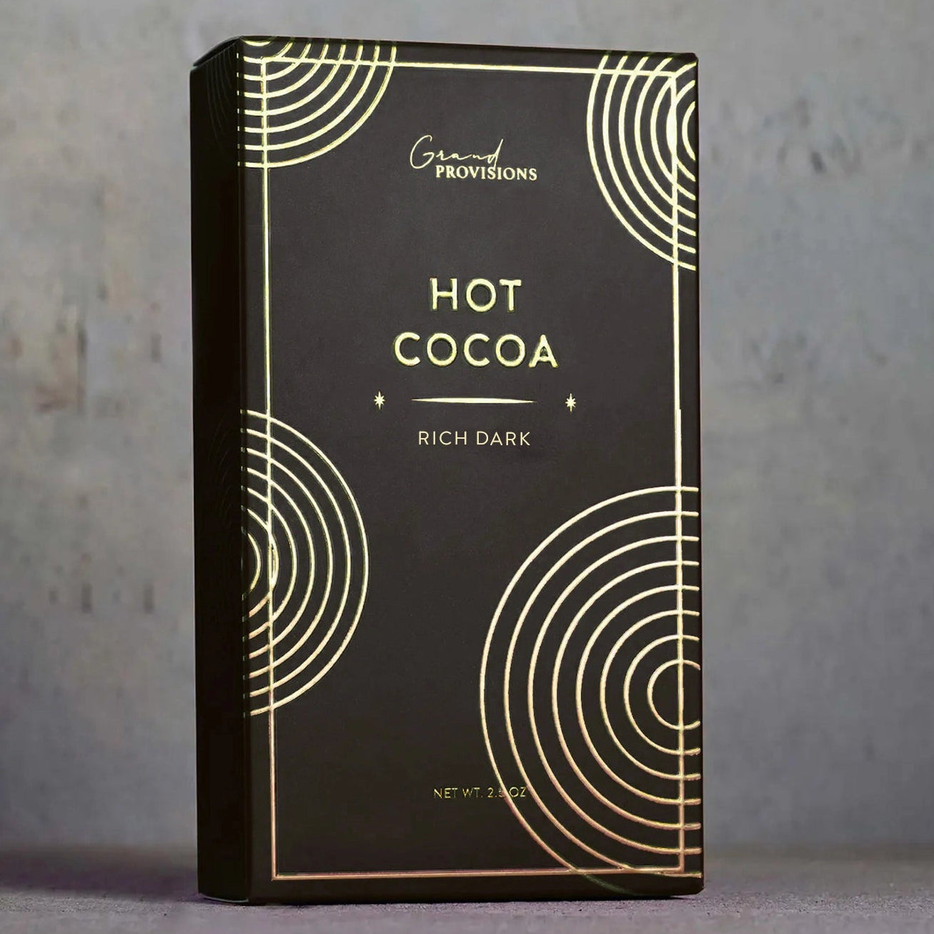 Black box of hot cocoa with gold text and design on a gray background