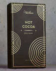 Black box of hot cocoa with gold text and design on a gray background