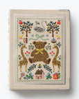 Embroidered notebook cover with teddy bear, giraffes, and nature-themed designs on a white background.