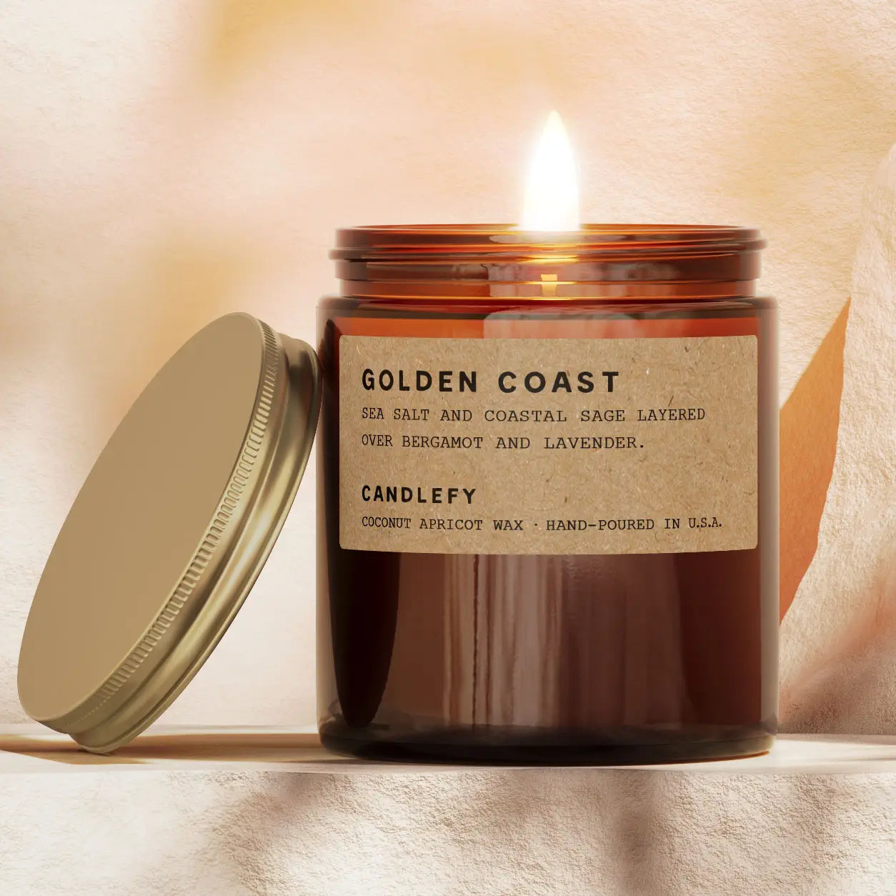 Candle with a label reading 'Tobacco + Rum' on a soft, warm background