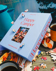 Happy Camper puzzle box with puzzle pieces and coffee cups on a table