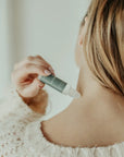 Person applying a skincare product to their neck with a dropper.