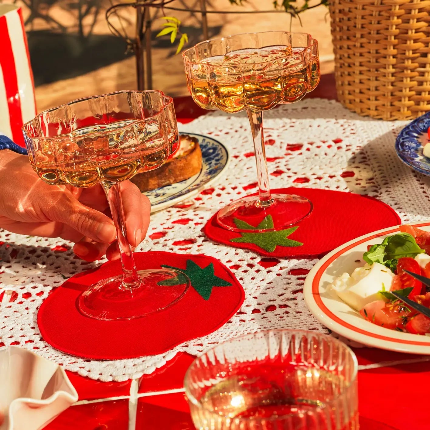 Two glasses of champagne on red coasters with a table setting including a salad.