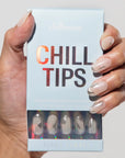 Hand holding a box of 'Chill Tips' with false nails.