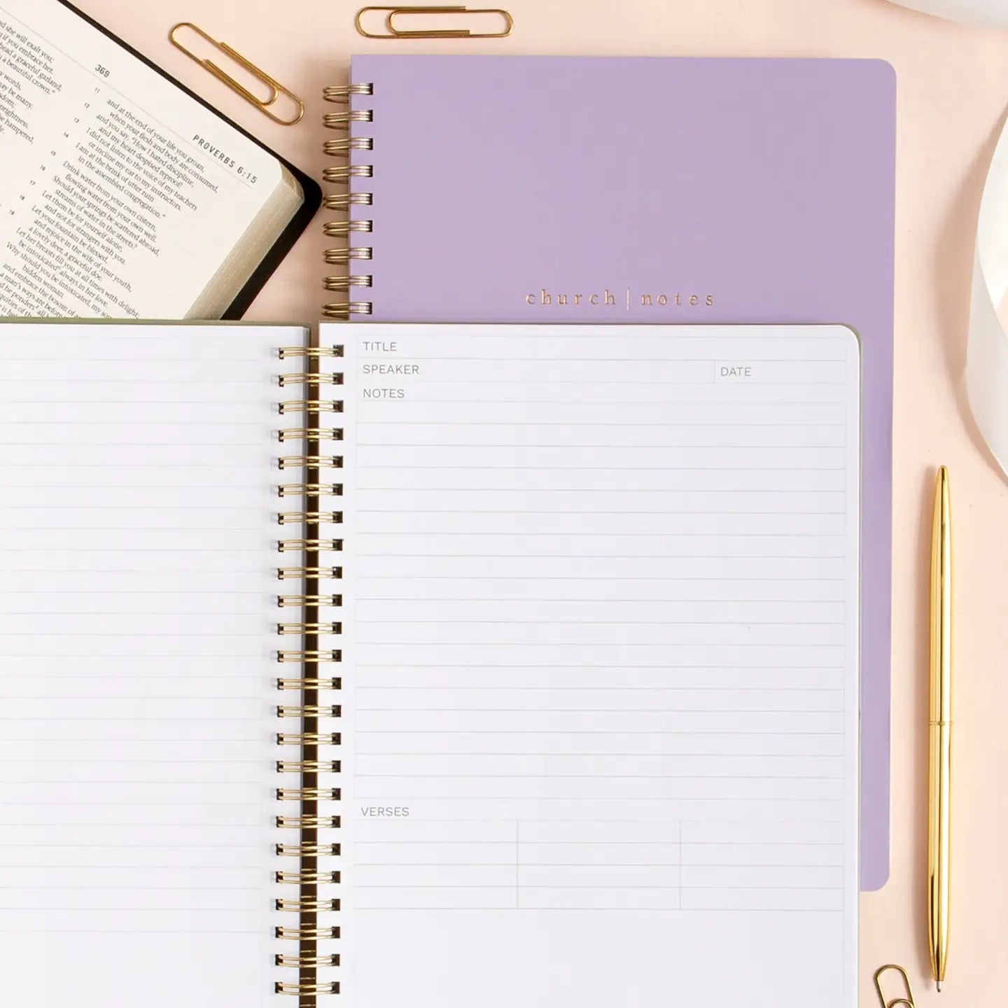 Open notebook with a purple cover and a gold pen on a light surface