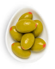 Green olives with red tips on a white plate against a white background