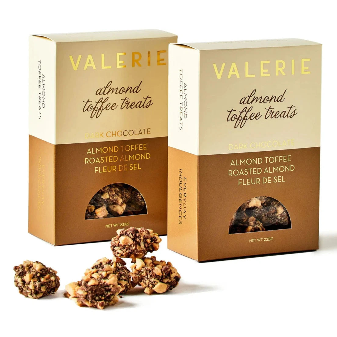 The image shows two boxes of "Valerie Almond Toffee Treats" in elegant packaging. Each box is labeled with "Dark Chocolate" and highlights ingredients such as "Almond Toffee," "Roasted Almond," and "Fleur de Sel." The top half of the box is beige, while the bottom is a rich brown, with a small circular window revealing the toffee treats inside. In front of the boxes, there are clusters of the almond toffee treats, which appear to be coated in chocolate and sprinkled with almond pieces.