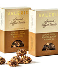 The image shows two boxes of "Valerie Almond Toffee Treats" in elegant packaging. Each box is labeled with "Dark Chocolate" and highlights ingredients such as "Almond Toffee," "Roasted Almond," and "Fleur de Sel." The top half of the box is beige, while the bottom is a rich brown, with a small circular window revealing the toffee treats inside. In front of the boxes, there are clusters of the almond toffee treats, which appear to be coated in chocolate and sprinkled with almond pieces.