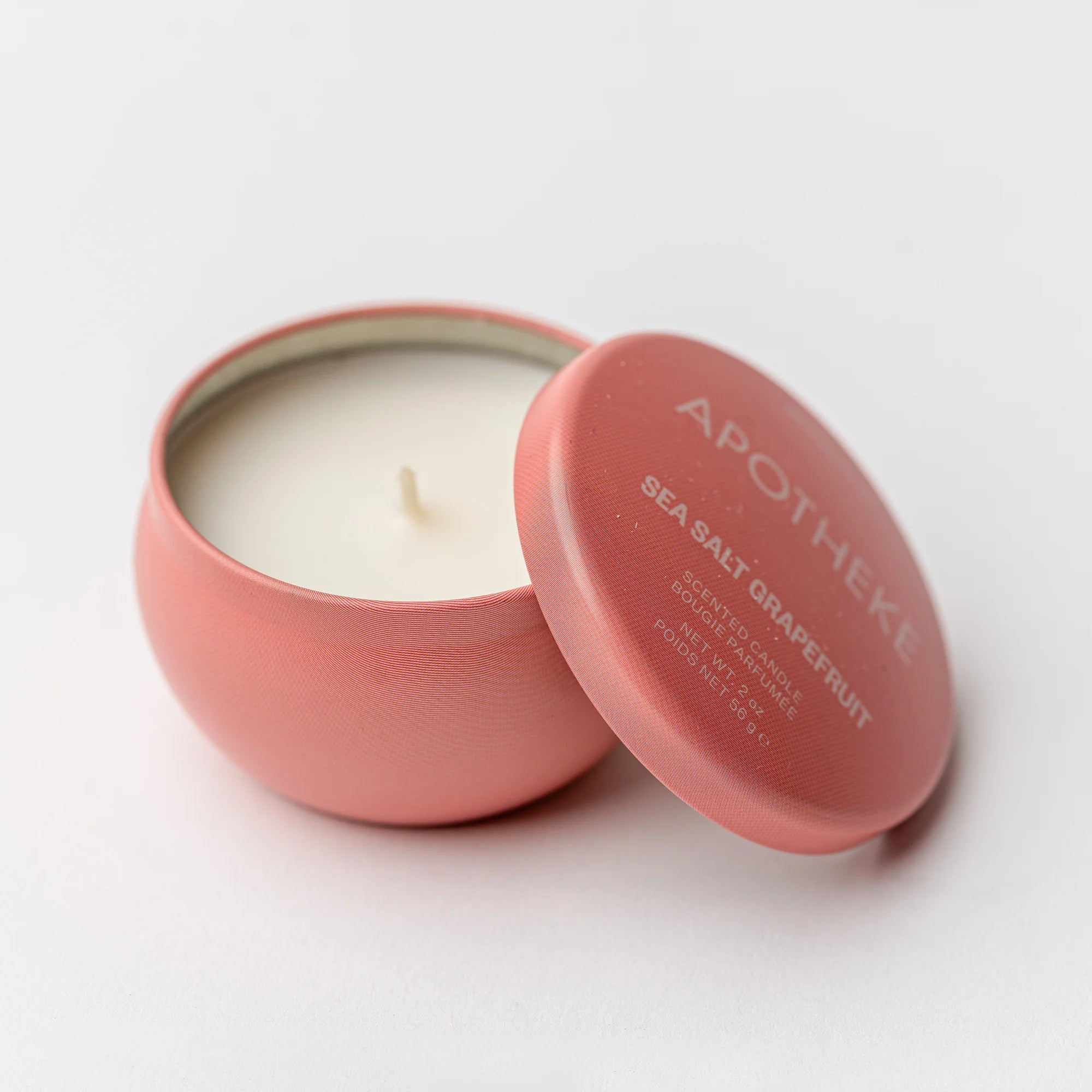 Pink candle in a tin with 'Apotheke' branding on a white background