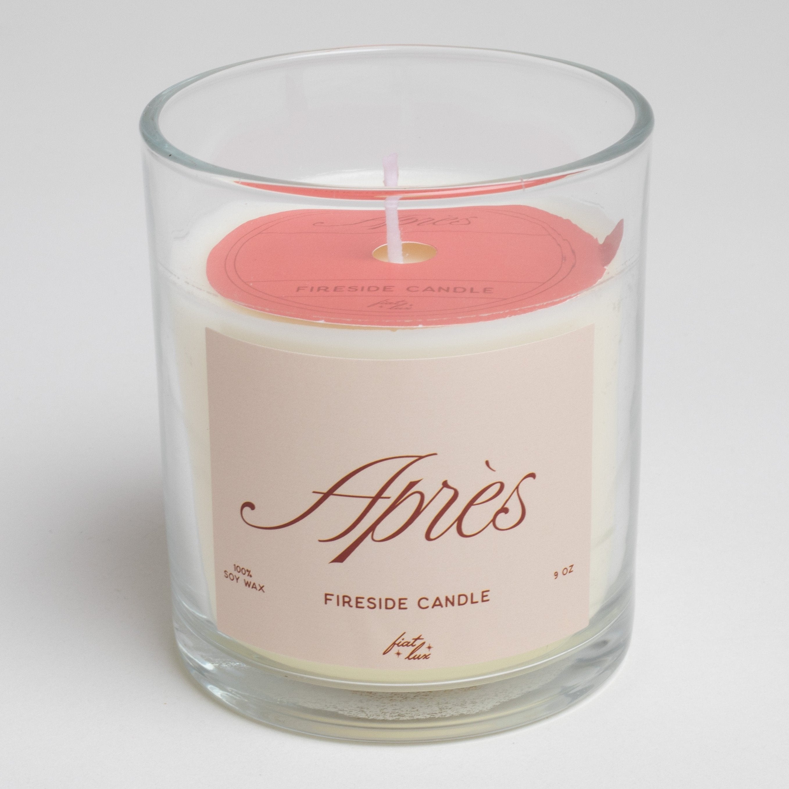 glass candle that has a light red label that says "APRÉS" on it