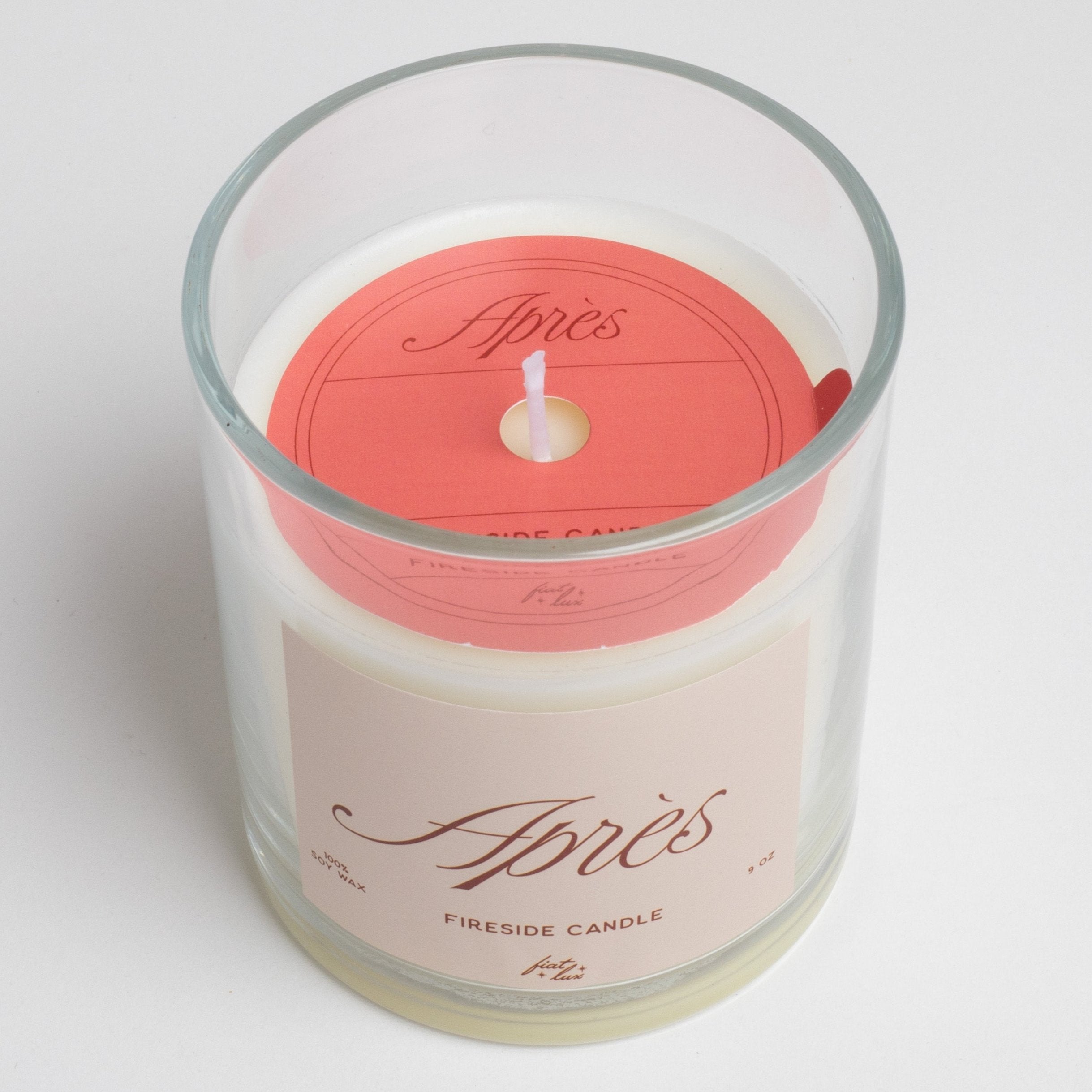 glass candle that has a light red label that says "APRÉS" on it