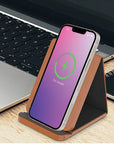 Smartphone on a stand with charging indicator next to a laptop on a desk