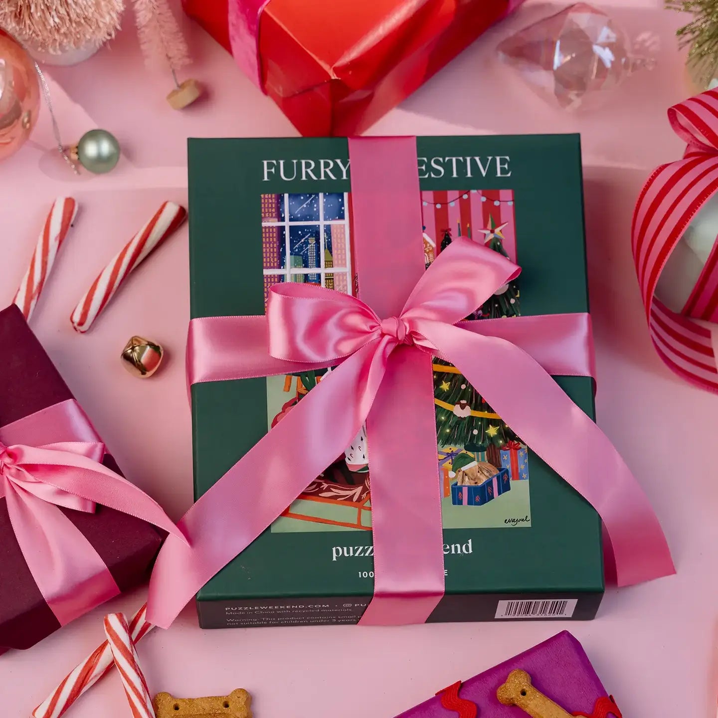 Gift box with a pink ribbon on a festive background with candy canes and ribbons.