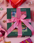 Gift box with a pink ribbon on a festive background with candy canes and ribbons.