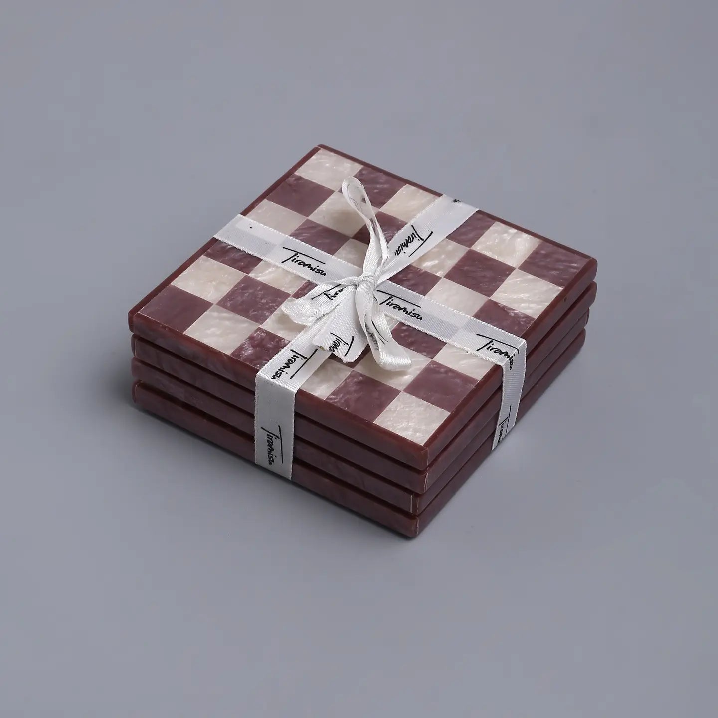 Set of checkered coasters tied with a ribbon on a gray background