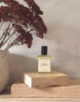Perfume bottle on a wooden block with dried flowers in the background