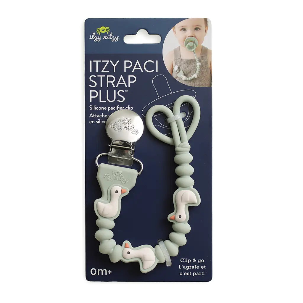 Itzy Paci Strap Plus silicone pacifier clip and strap set in sage green, featuring duck-shaped beads and a silver metal clip, displayed on its dark blue retail packaging card.