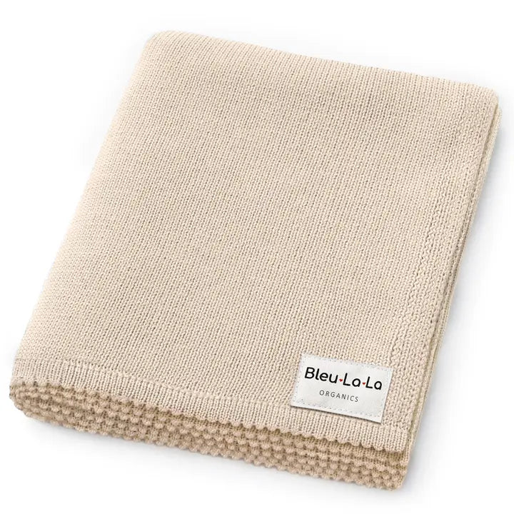 A folded beige knit blanket with a textured ribbed edge and a white label reading 'Bleu-La-Lo ORGANICS', shown on a clean white background.