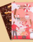 Dark chocolate bar with a peppermint pretzel flavor and its packaging on a beige background