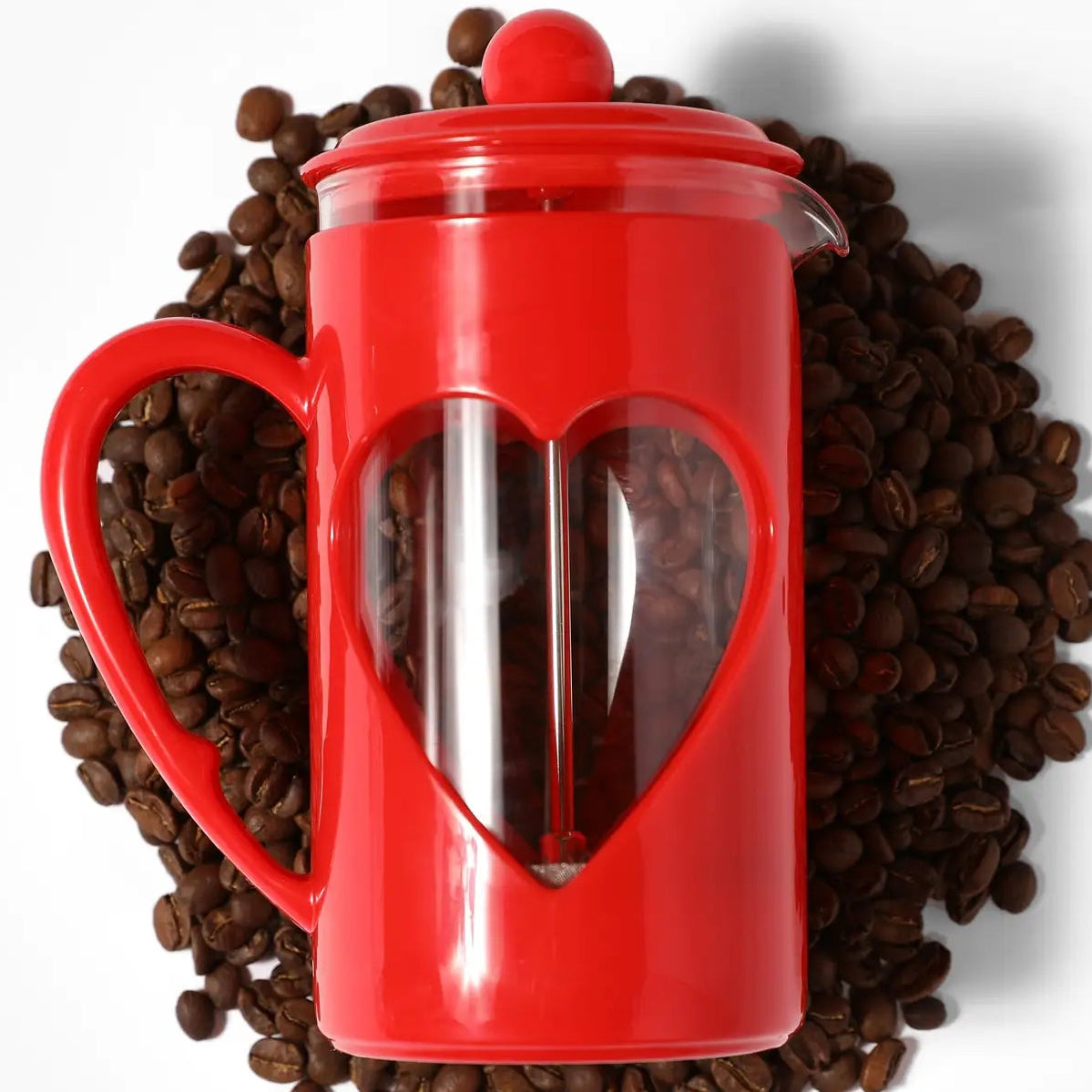 Red French press coffee maker on a bed of coffee beans