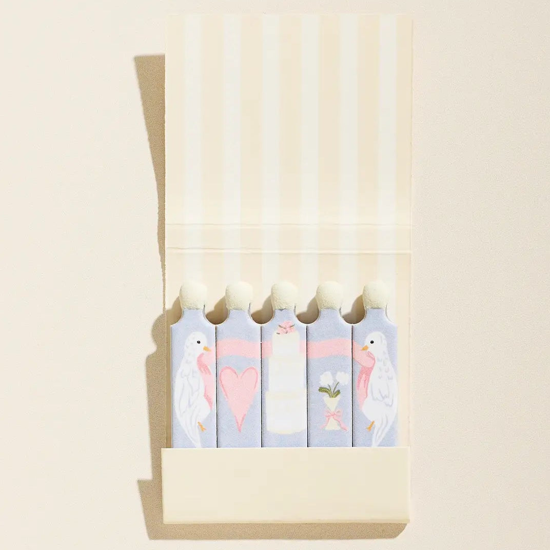 Set of colorful flamingo-themed notepads in a beige holder on a light beige background