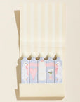 Set of colorful flamingo-themed notepads in a beige holder on a light beige background