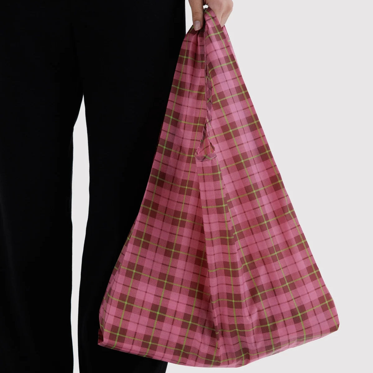 Person holding a pink plaid bag against a white background