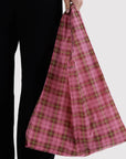 Person holding a pink plaid bag against a white background