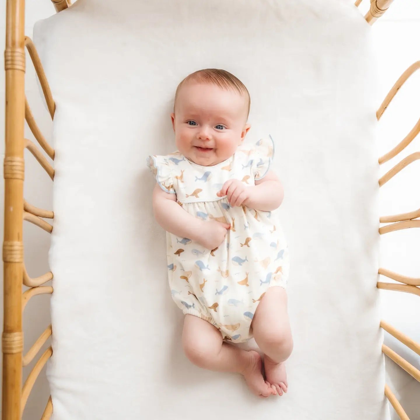 baby wearing the whale tales romper in a crib
