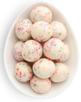 white chocolate balls with colorful sprinkles in them inside white oval dish