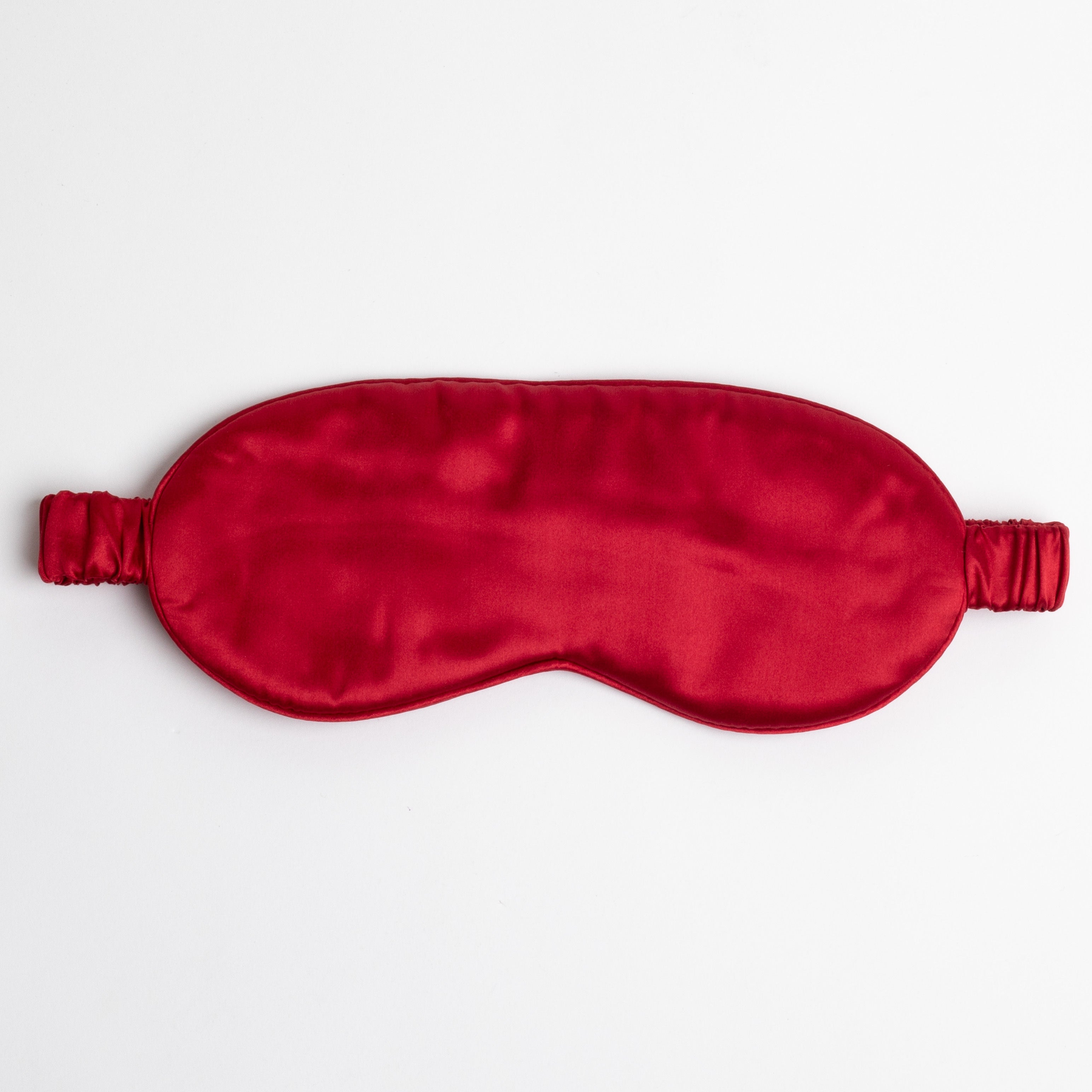 Red silk sleep mask on white background.