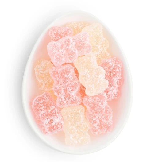 A white dish filled with pastel-colored gummy bears, coated in a sparkling sugar finish, arranged neatly within the dish.