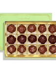 A box of 15 chocolate truffles in a gold tray, with a light green Sugarfina brand box behind it on a white background.