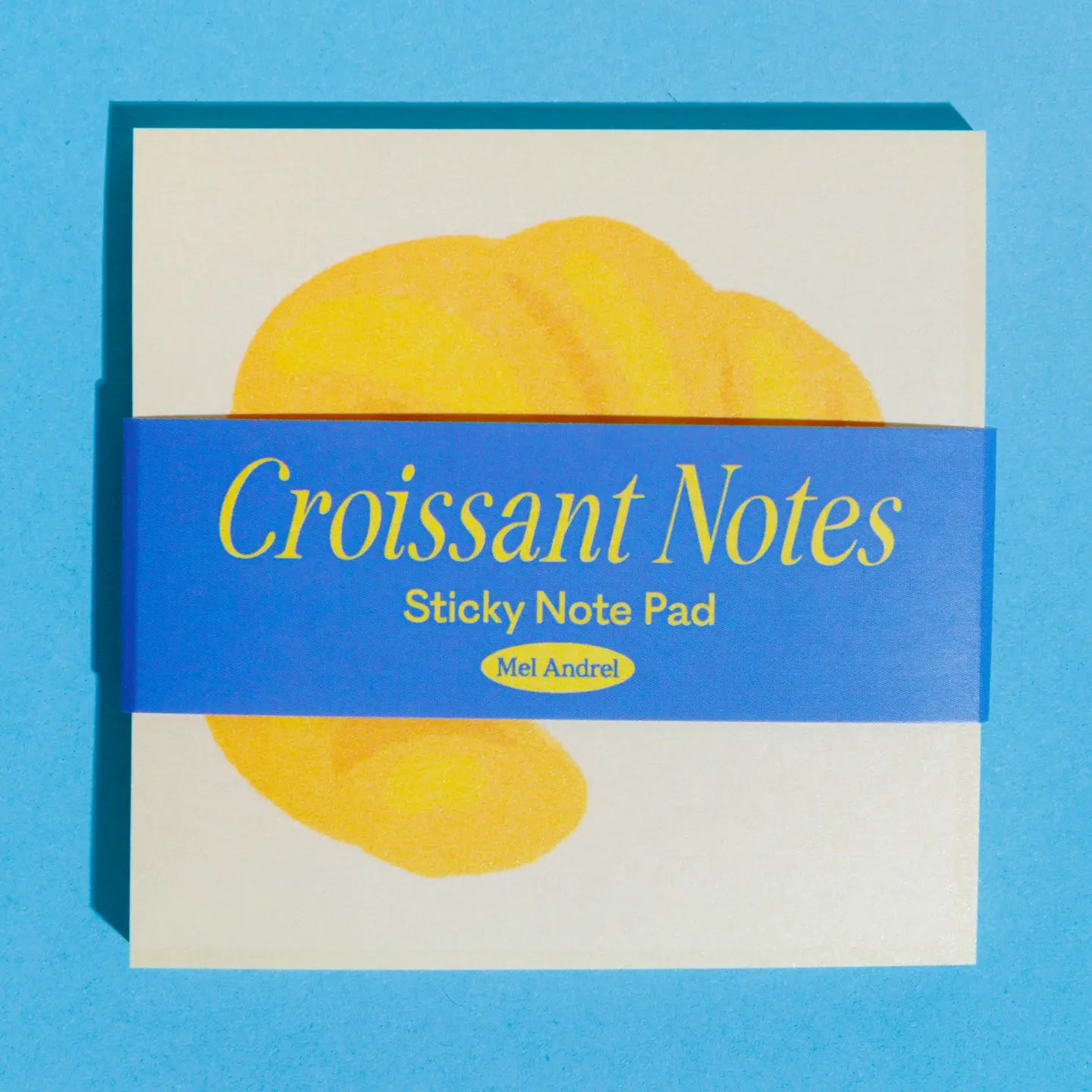 Sticky note pad with croissant design on a blue background