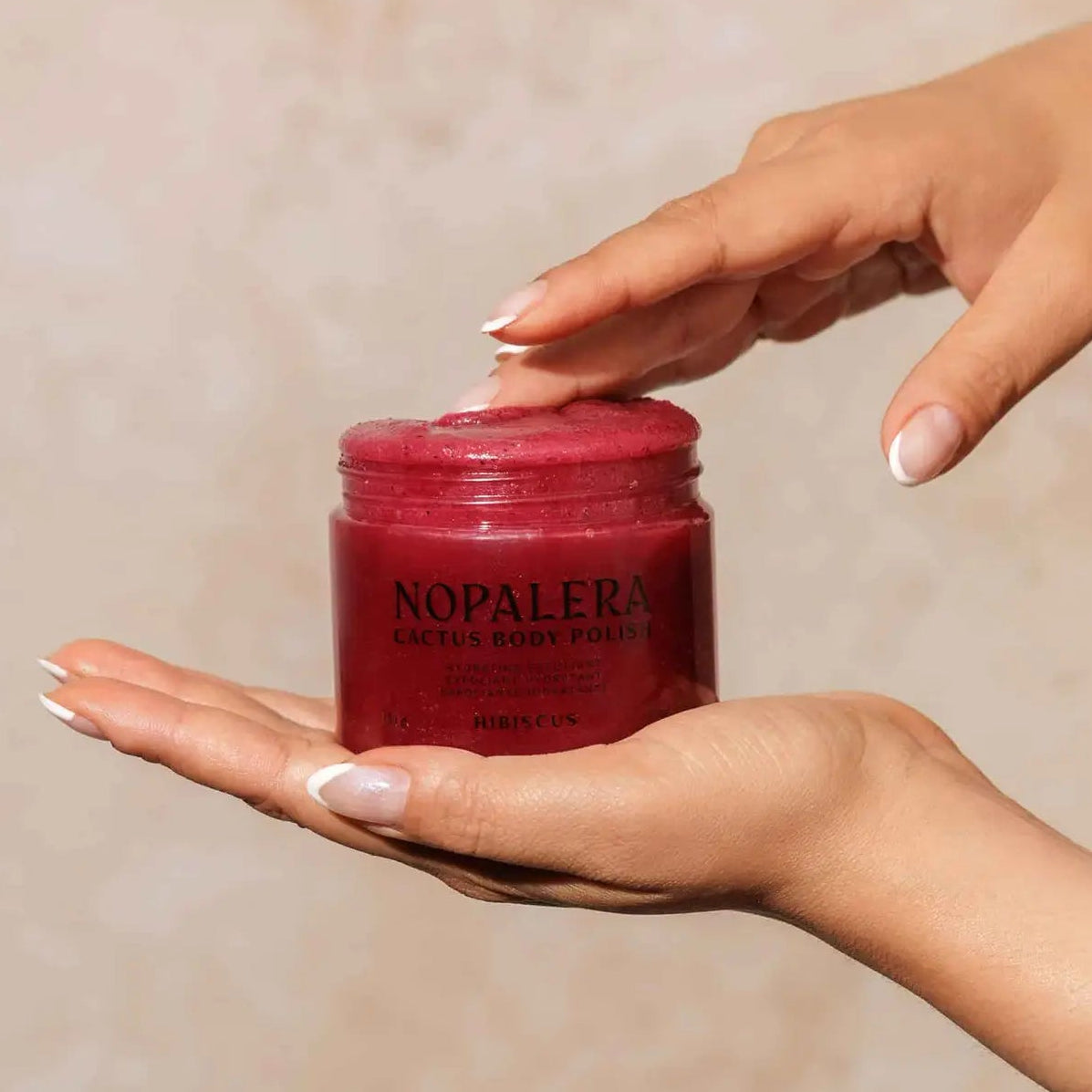 Red jar labeled 'Nopalera' held by a hand against a neutral background