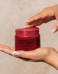 Red jar labeled 'Nopalera' held by a hand against a neutral background