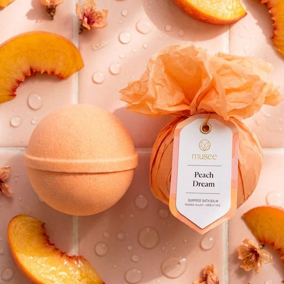 Peach-themed bath bomb with packaging on a background of peach slices and flowers.