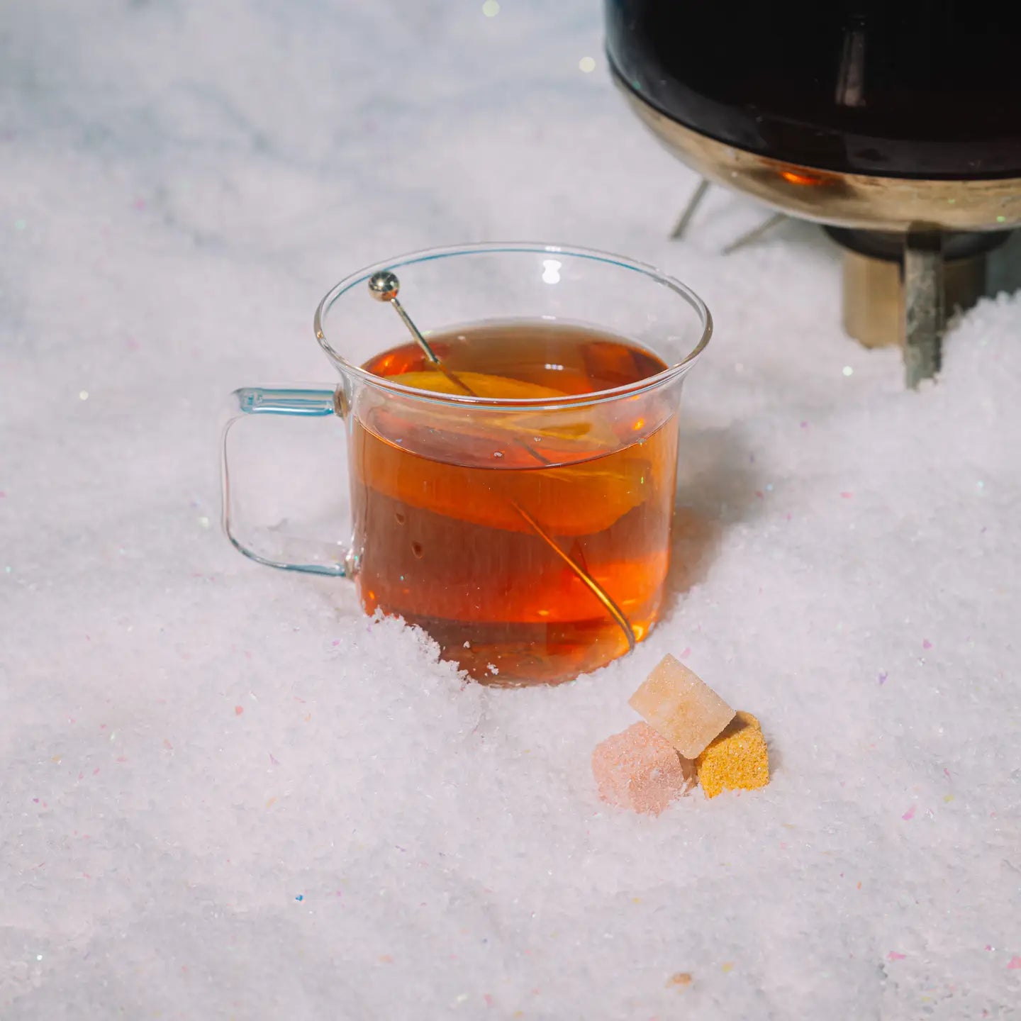 Clear mug of hot tea with a teabag on a snowy surface