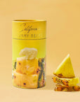 yellow cylinder with gold text on the top. has picture of bear gummy sitting on top of pineapple