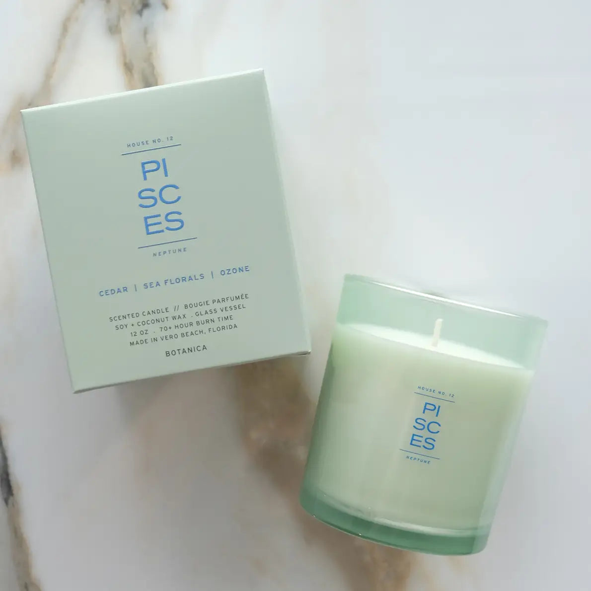 Green candle and packaging labeled 'Pisces' on a marble surface