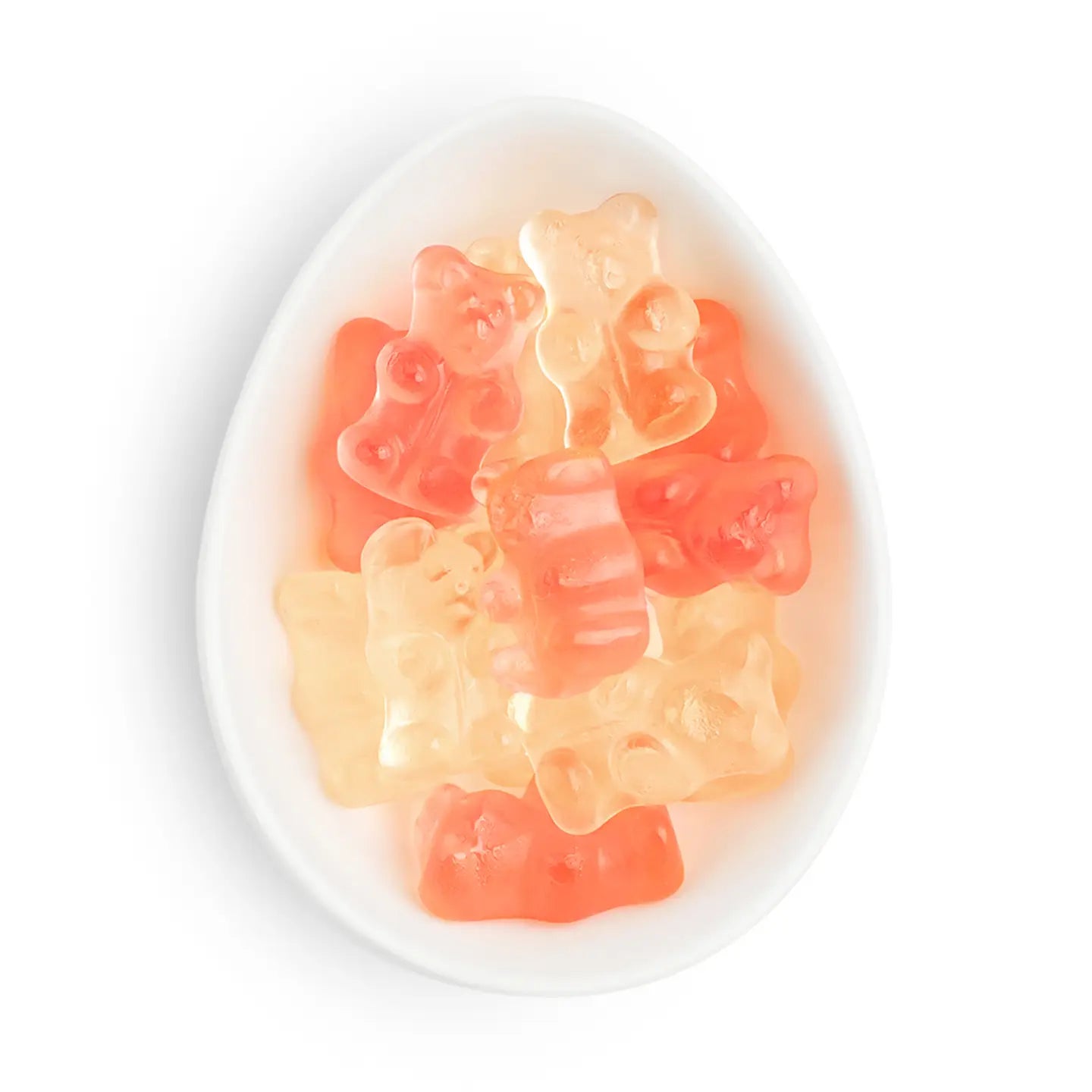 Gummy bear candies in translucent orange, pink, and pale yellow colors, arranged inside a white oval dish on a white background.