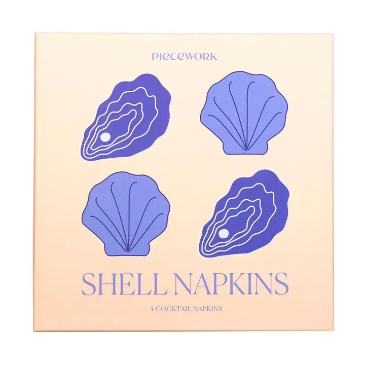 A square product box for Piecework Shell Napkins, featuring a light peach background with purple illustrations of two oysters and two scallop shells, and the text 'SHELL NAPKINS' and '4 COCKTAIL NAPKINS'.