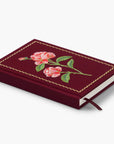 maroon fabric journal with pink roses embroidered on it