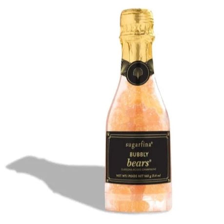 A small, clear bottle shaped like a champagne bottle, filled with sparkling sugar-coated gummy bears. The label reads "Sugarfina Bubbly Bears," and the bottle has a gold foil top resembling a champagne cork.