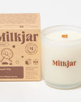 clear glass candle with "MILKJAR" printed on it in brown next to packaging box 