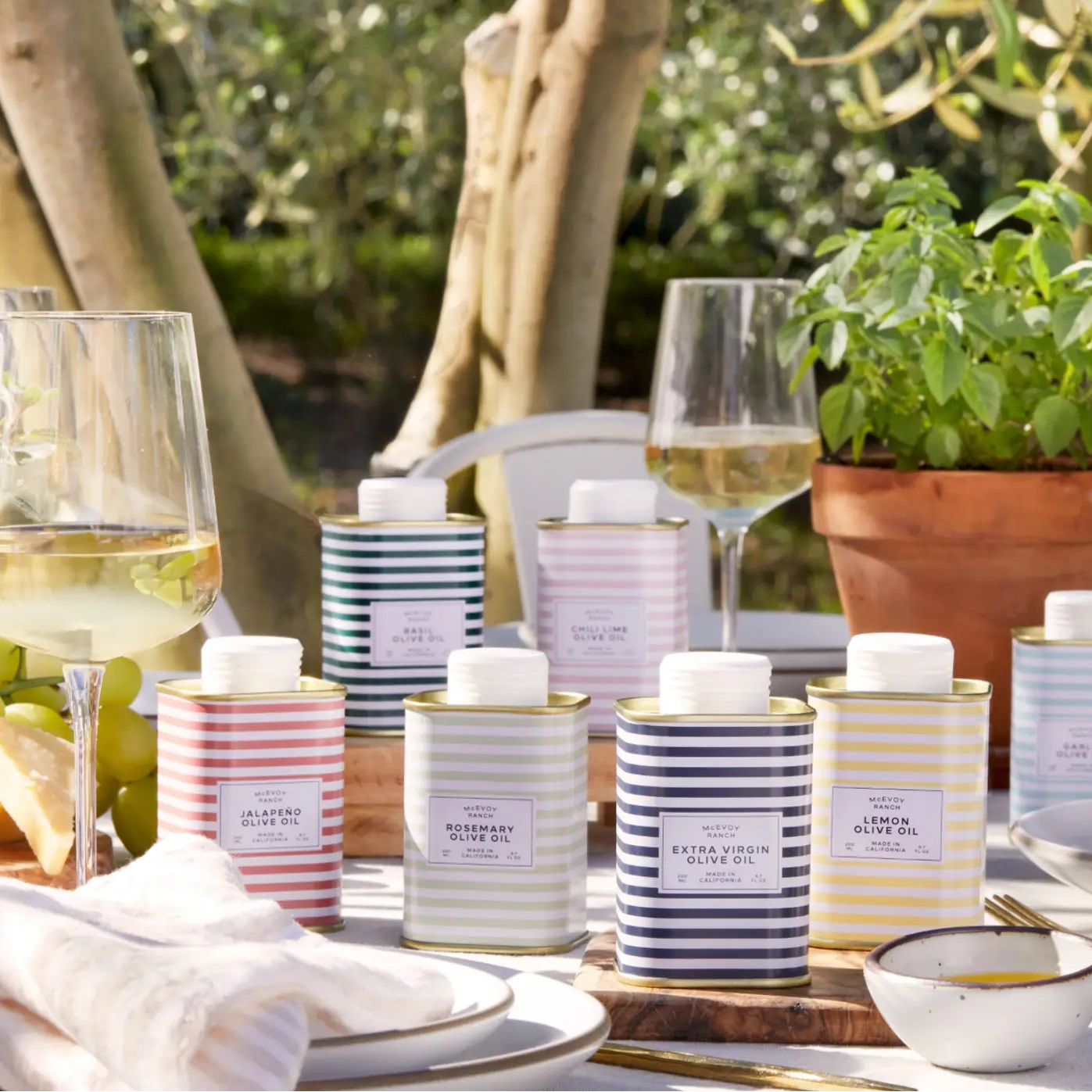 Table setting with striped candles and glasses of white wine outdoors.