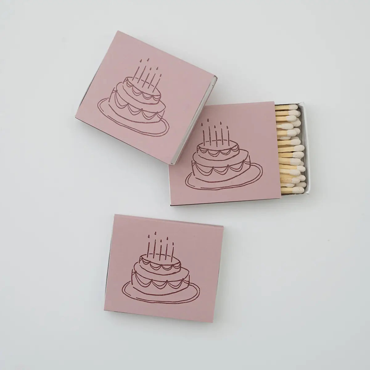 Matchboxes with a cake illustration on pink boxes